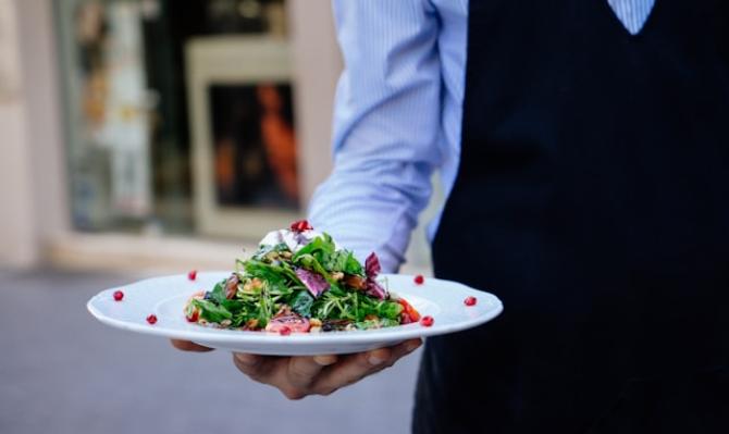 Camarero con un plato de ensalada en la mano. Photo by Lefteris Kallergis on Unsplash