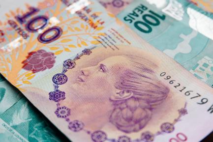 Billete de cien pesos argentinos sobre un billete de 100 reales brasileños